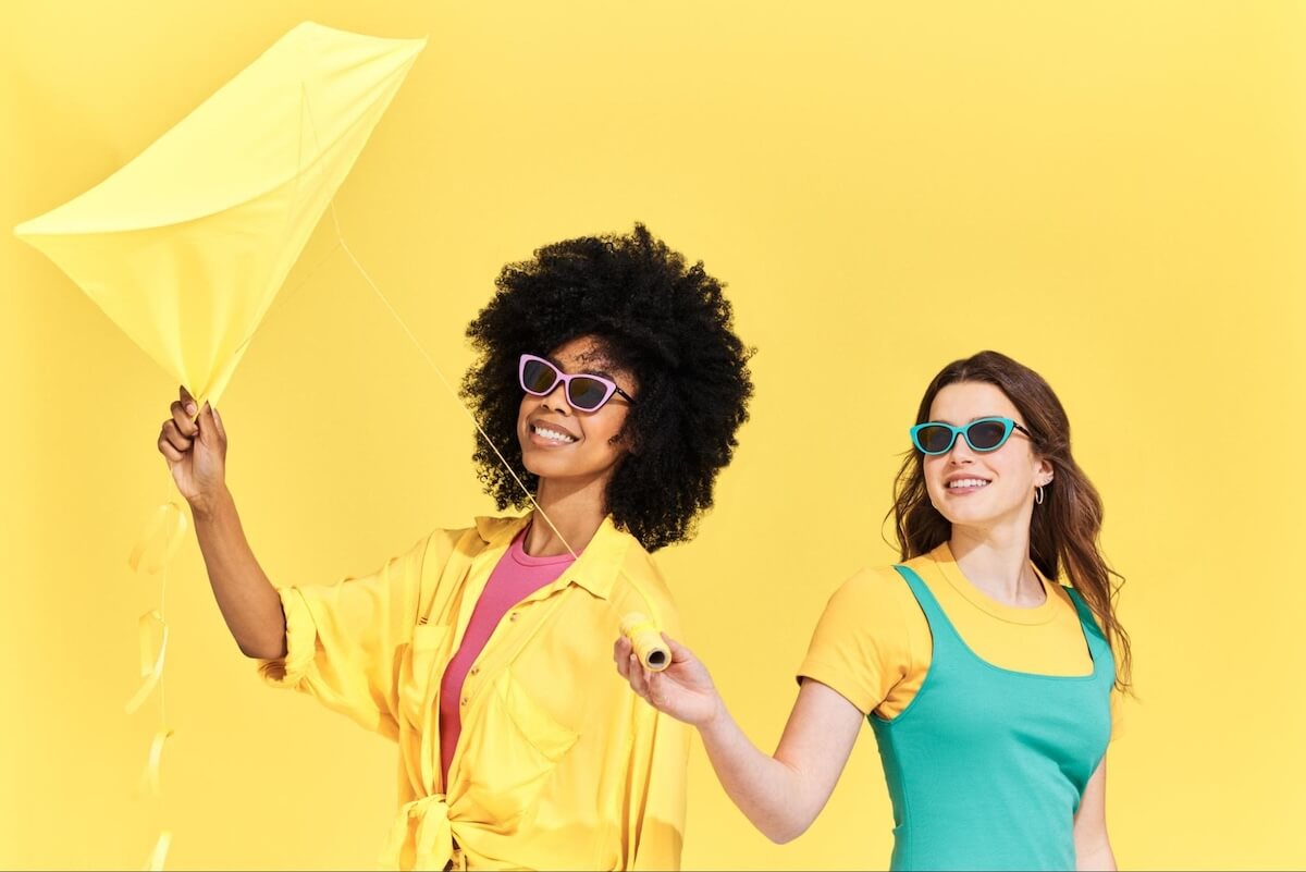 2 women wearing cat eye sunglasses while holding a kite