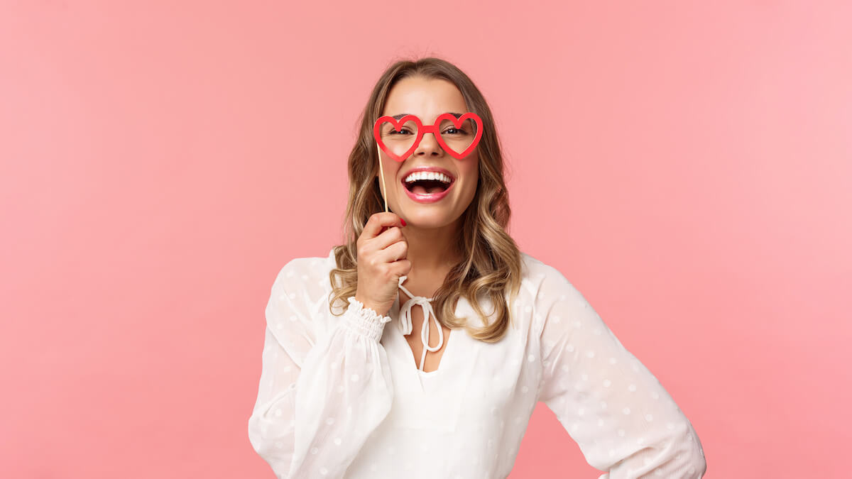 Brides with glasses: woman holding a heart-shaped glasses mask