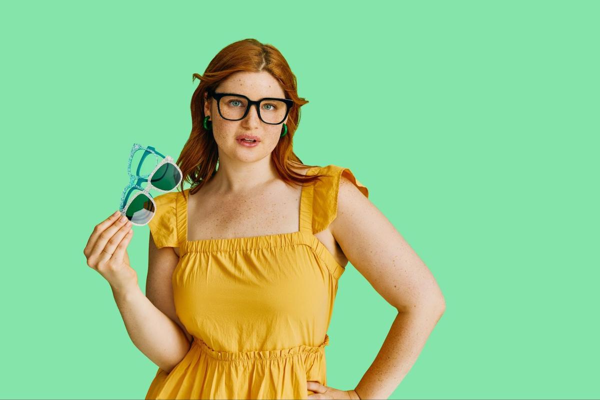 Glasses for light sensitivity: woman wearing a pair of eyeglasses while holding 3 pairs of eyeglasses