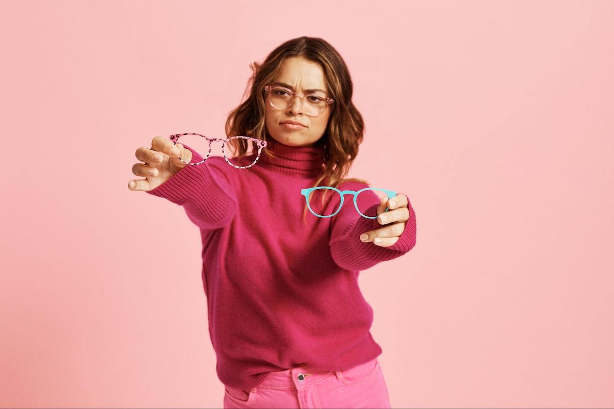 Glasses for square face shape: woman choosing between two pairs of eyeglasses