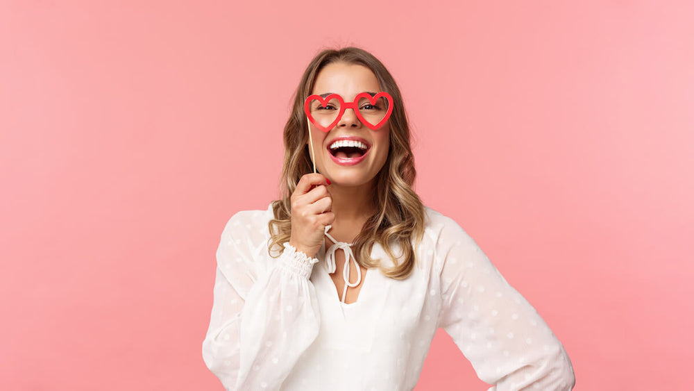 Brides with glasses: woman holding a heart-shaped glasses mask
