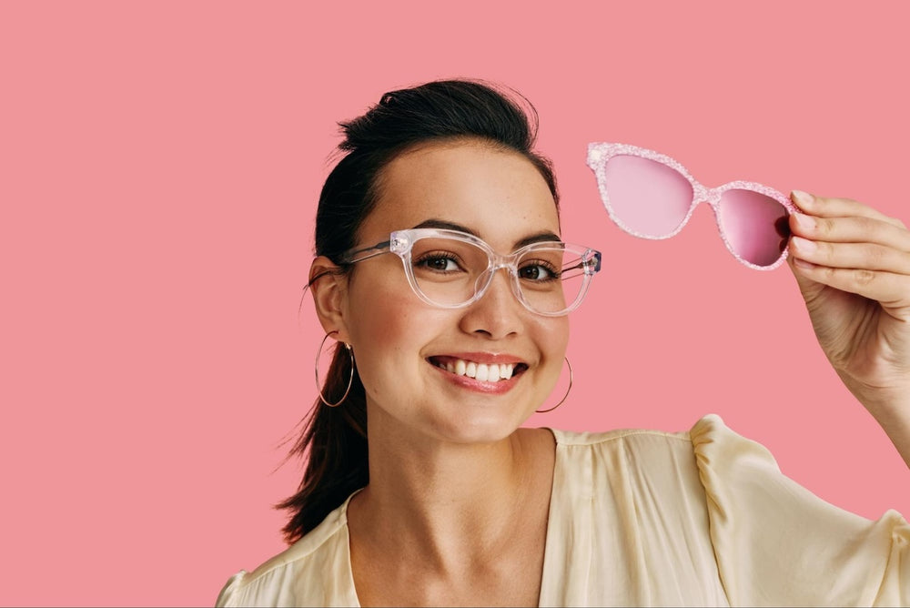 How to get scratches out of glasses: woman smiling at the camera while holding a pair of eyeglasses